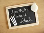 Foto: Kreidetafel mit Kreide und Schwämmchen, auf der Tafel in Schulschrift "Apotheke macht Schule".